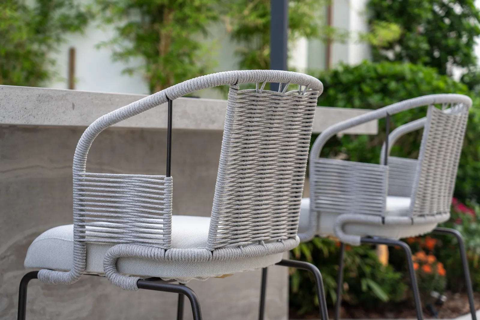 Outdoor dining chairs beside planted borders