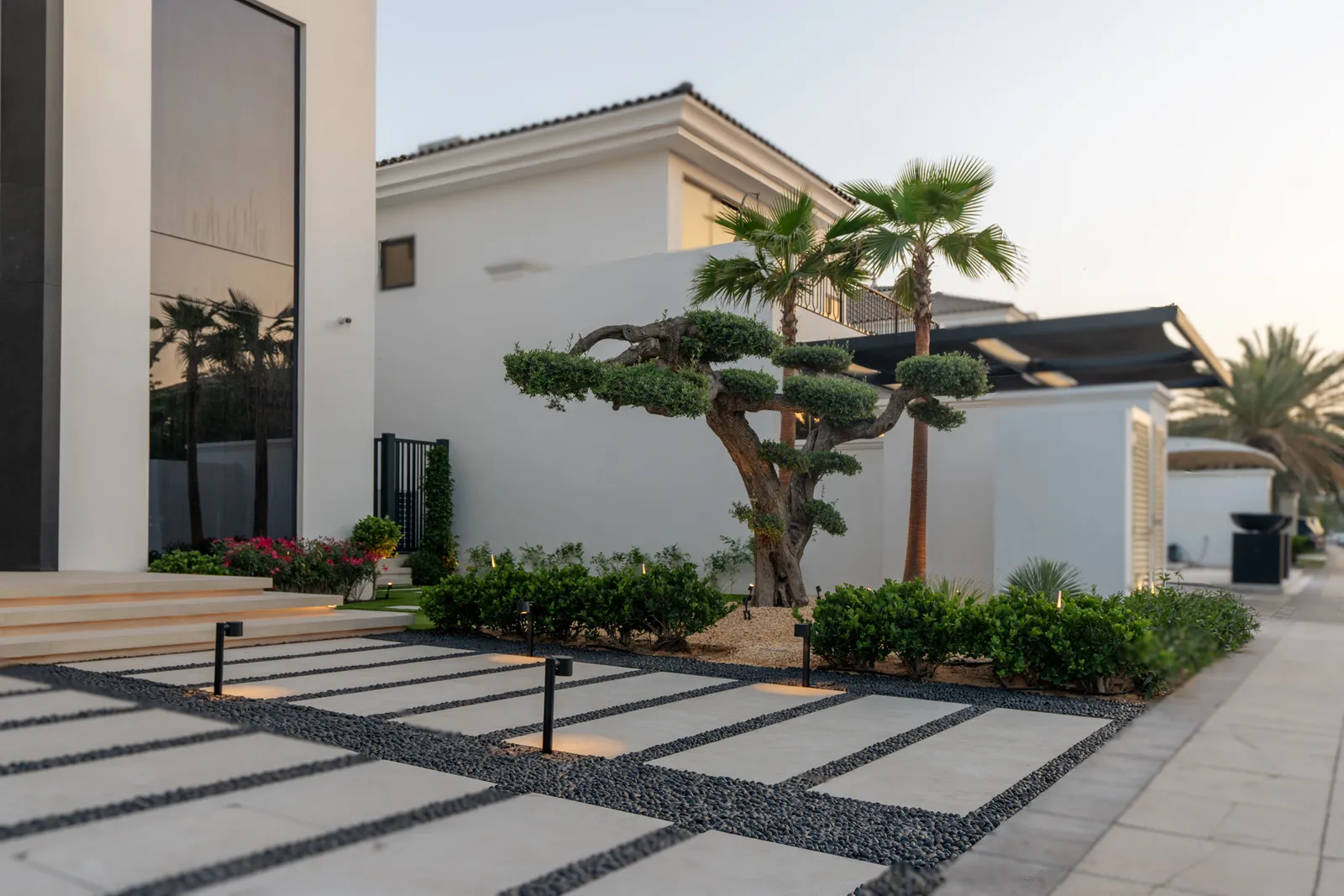 Bonsai-form trees and gravel detailing along the approach