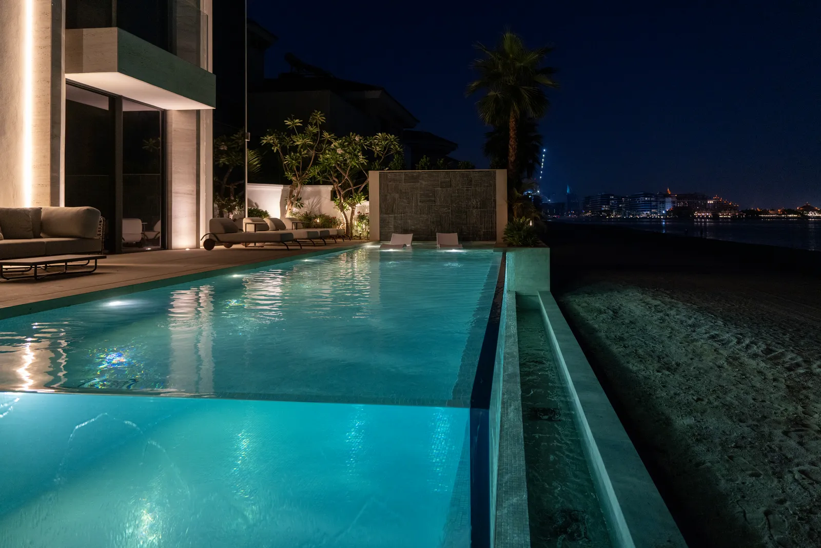 Night view along the lit infinity pool towards the sea