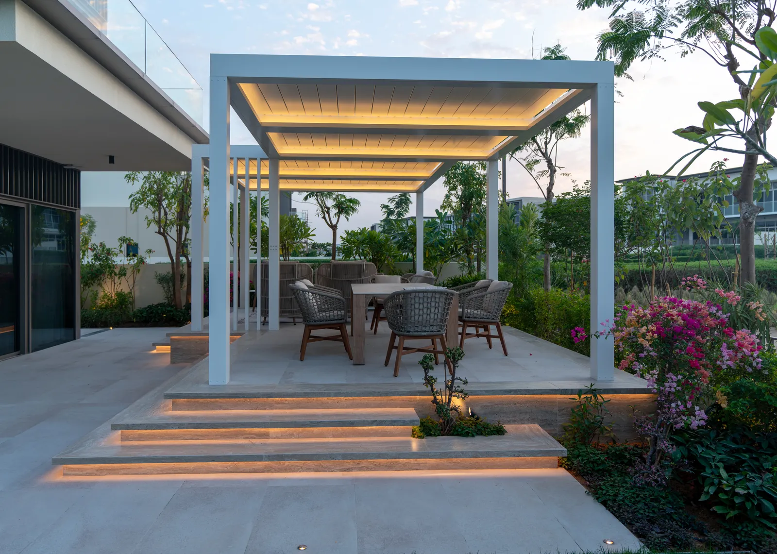 Illuminated steps rising to the pergola at dusk