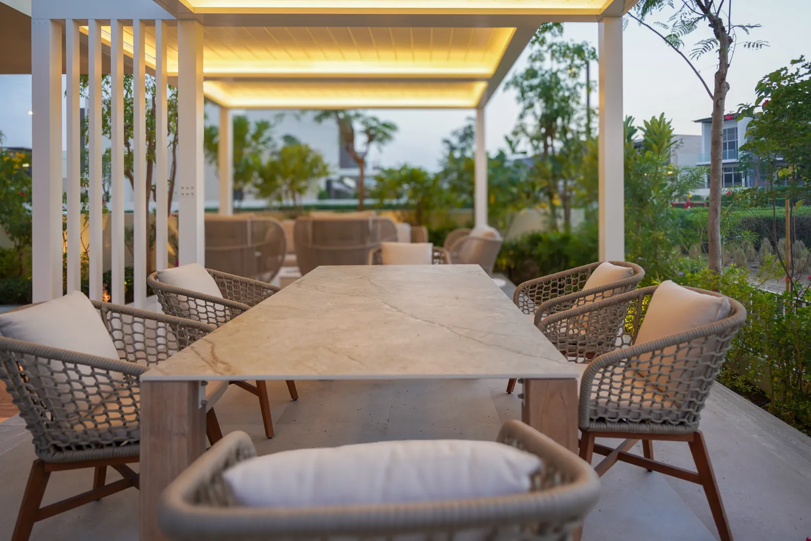 Dining table set beneath the warm-lit pergola