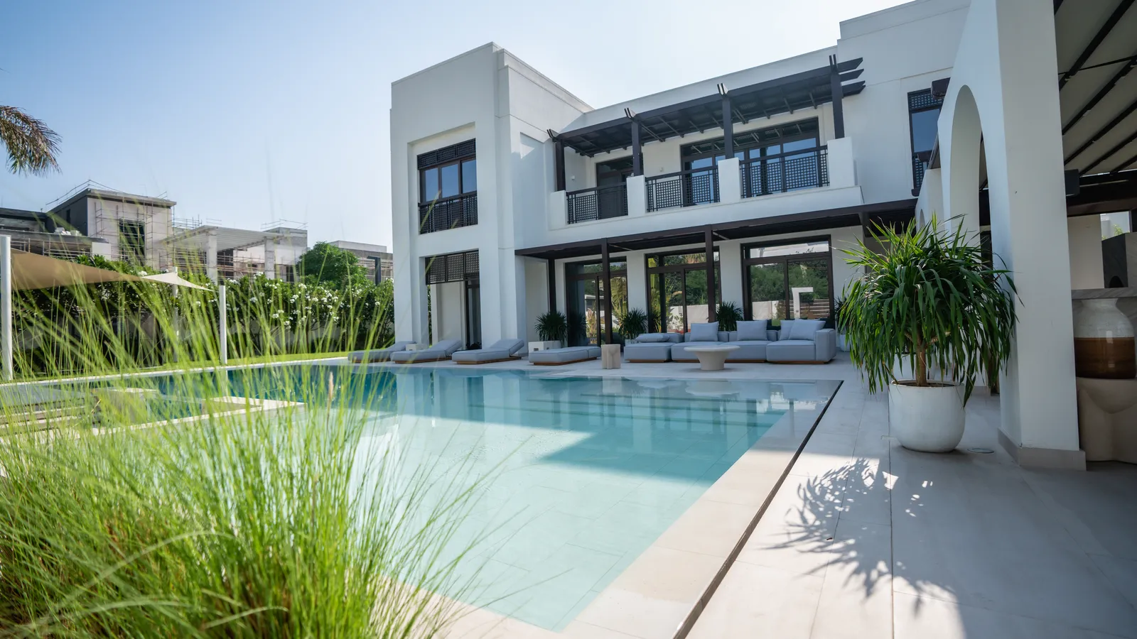 The villa seen across the pool through ornamental grasses