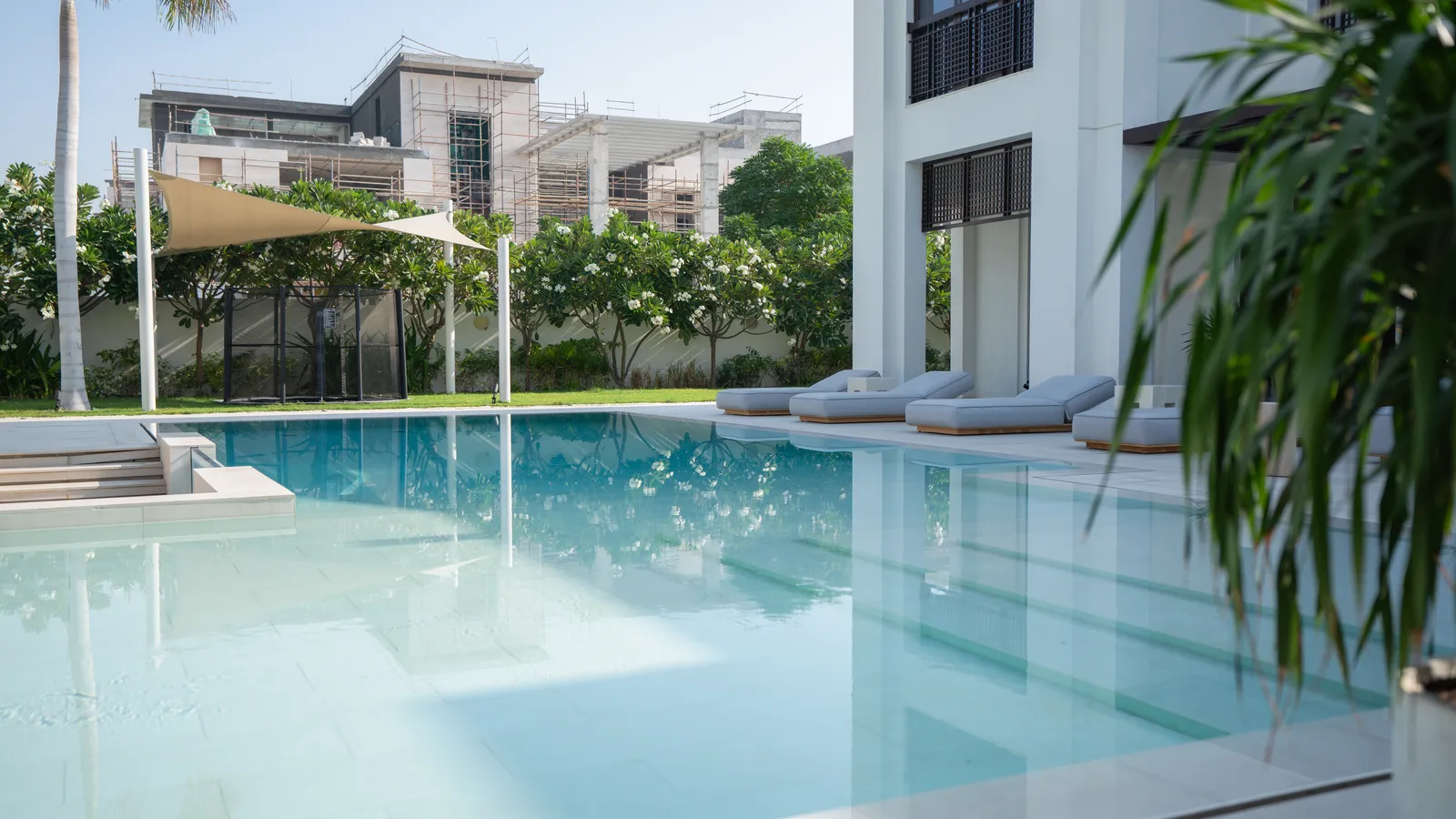 Shade sail drawn over the loungers at the pool edge