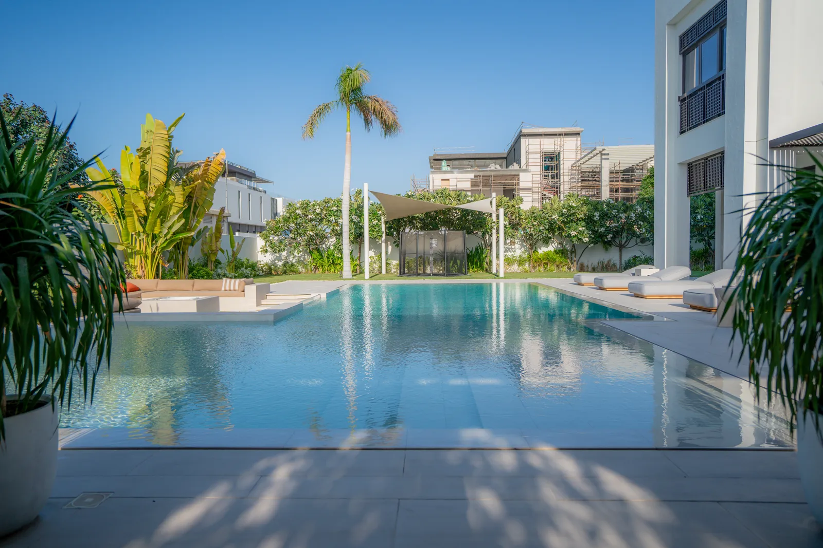 The pool holding a still reflection of the villa and palms